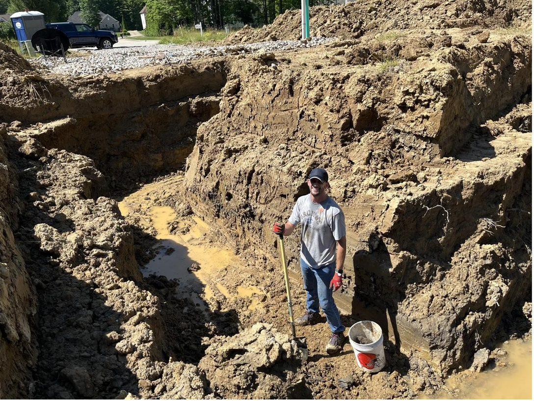 Matt Jones on a job site, standing in an excavation with a shovel